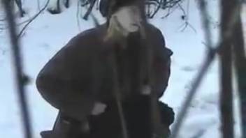 Odd woman urinating in the shrubs during winter